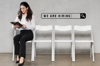A woman sitting on a chair with a tablet, displaying "We are hiring" for a temporary finance position.