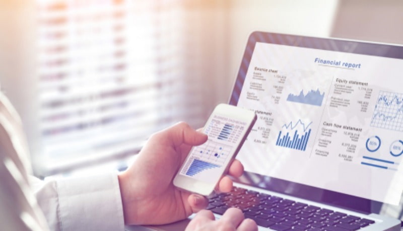 Man looking at financial report on computer and phone.