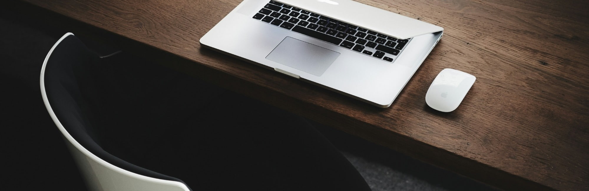 A laptop rests on a wooden desk, showcasing a modern workspace setup.