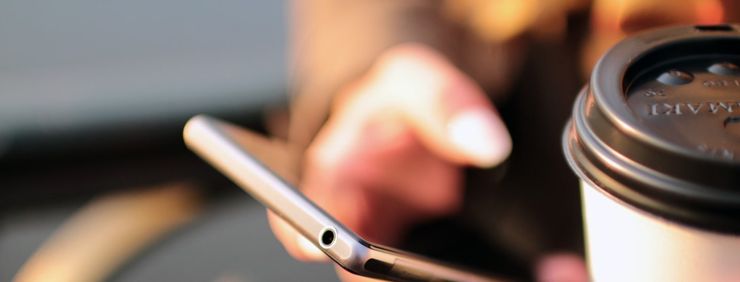 Close up of person holding coffee and mobile phone on the go