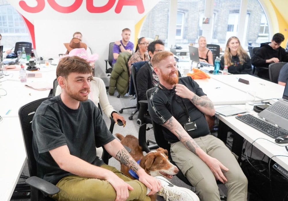 Employees smiling and a dog at workplace presentation in London office