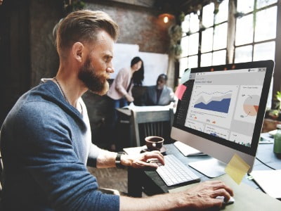 Man with beard in cool office looking at open laptop