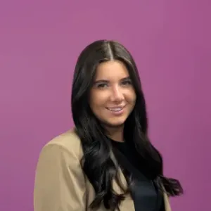 A woman with long dark hair wearing a black shirt, looking directly at the camera with a neutral expression.