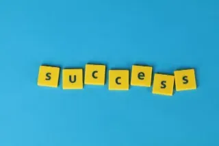 The word "success" formed with yellow tiles against a blue backdrop, representing the concept of long-term success.