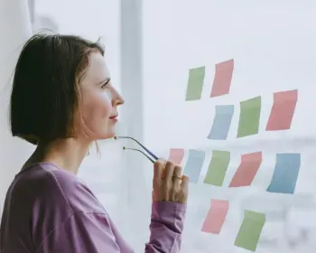 A woman studies sticky notes affixed to a window, representing her strategic approach to making confident decisions.