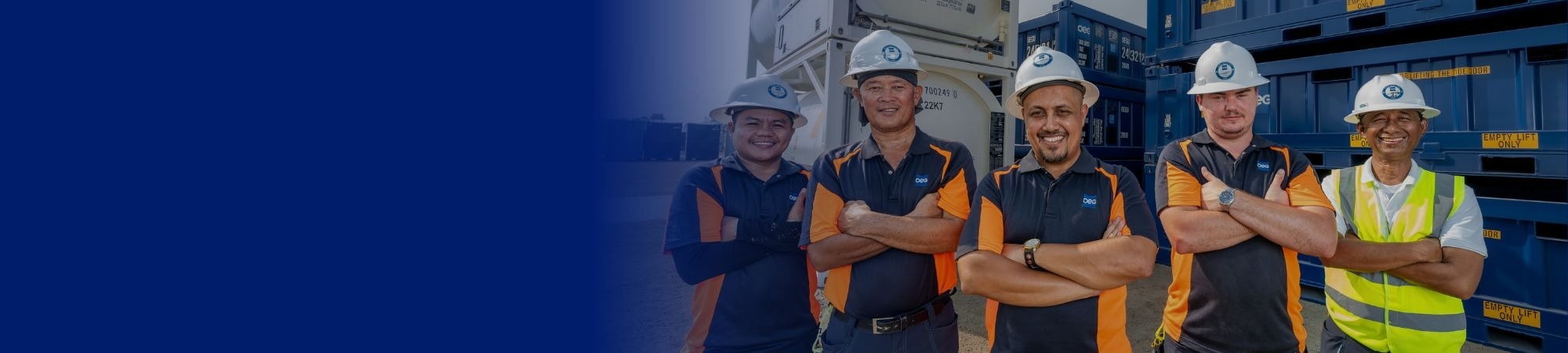 Five workers in hard hats with arms folded smiling.