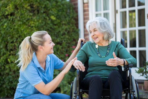 health care assistant talking to a lady in a wheelchair.