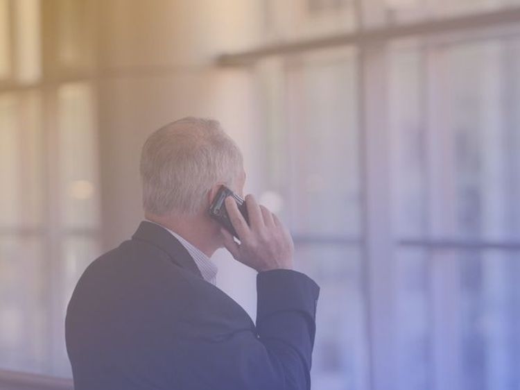 older business man in suit on cellphone looking at window