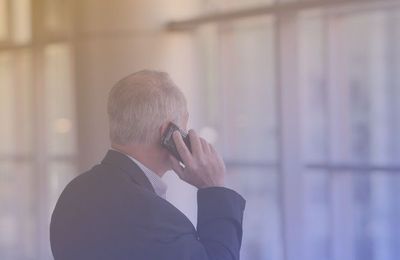 older business man in suit on cellphone looking at window