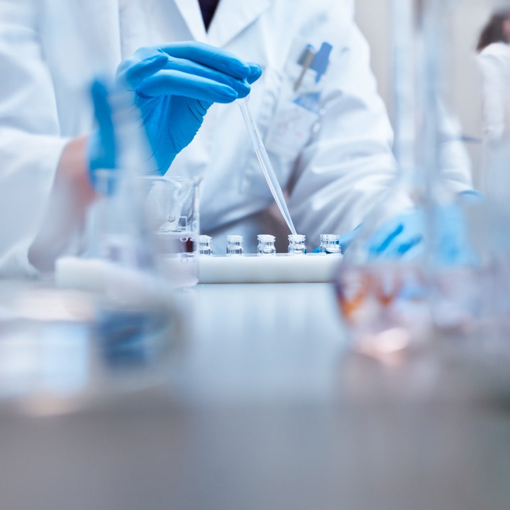 Scientist filling vials with solution through pipette in test tube rack in a science lab