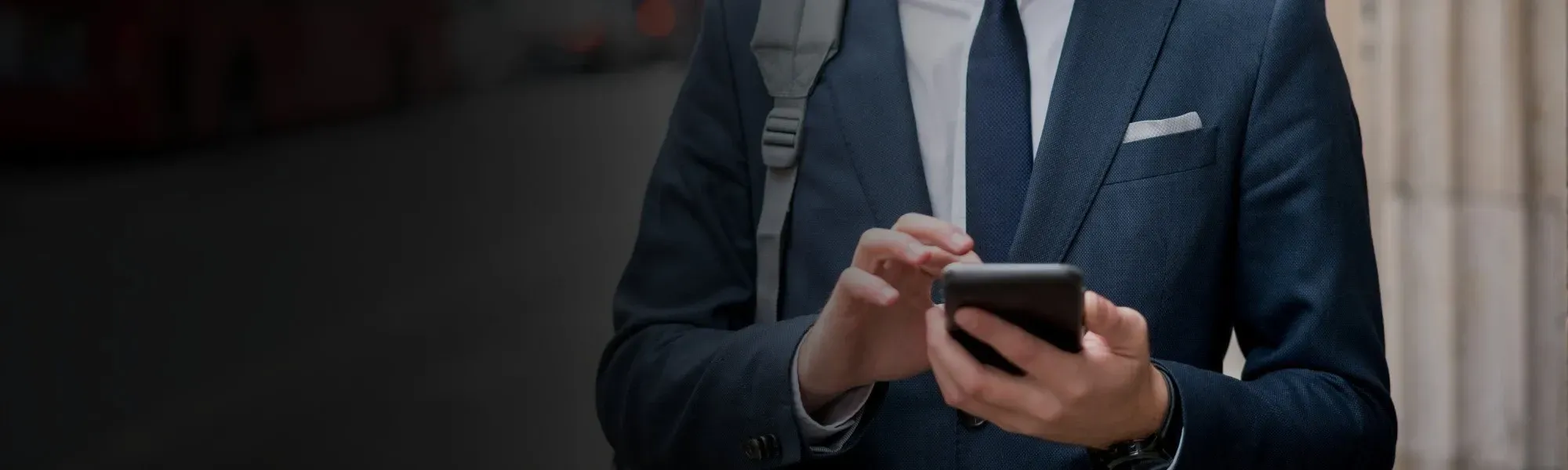 Young business man in suit texting on the street looking at phone