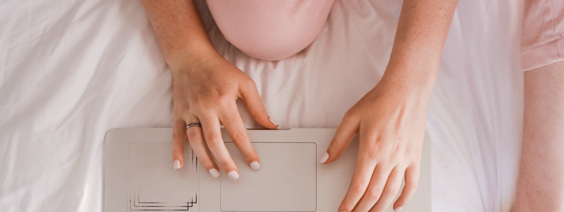 Woman's hands using a computer in bed