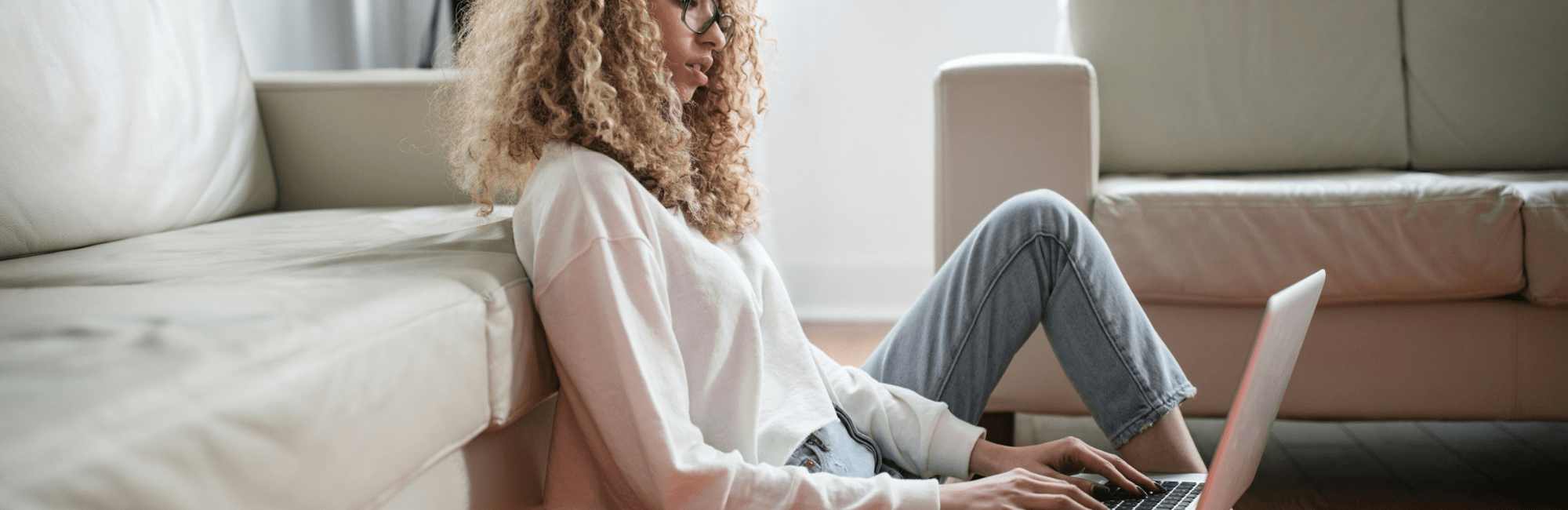 A woman sitting on the floor, focused on her laptop, illustrating a work-life balance moment.