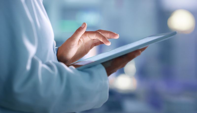 A person in a labcoat using a tablet