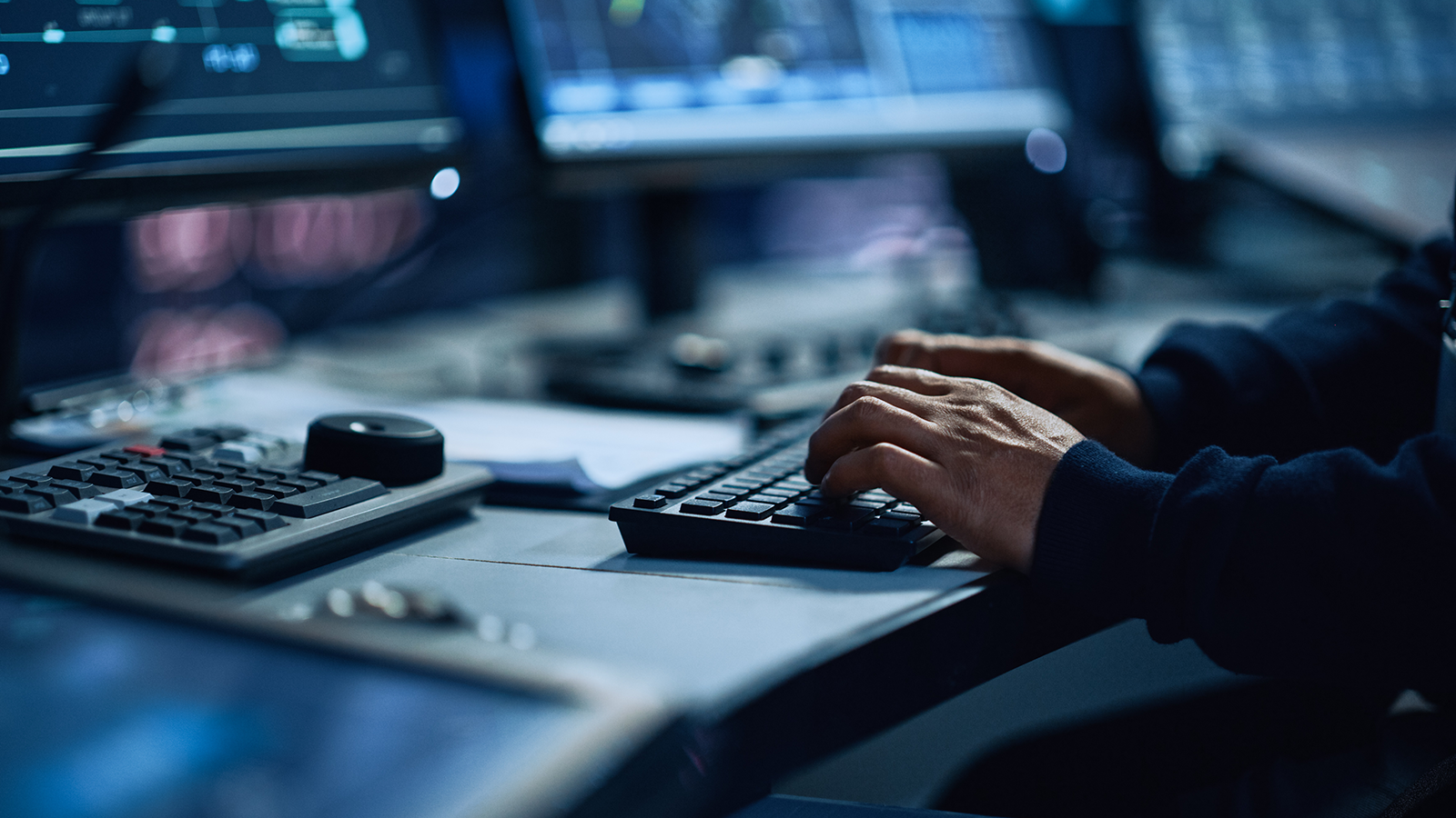 Someone at a computer desk typing on a keyboard 