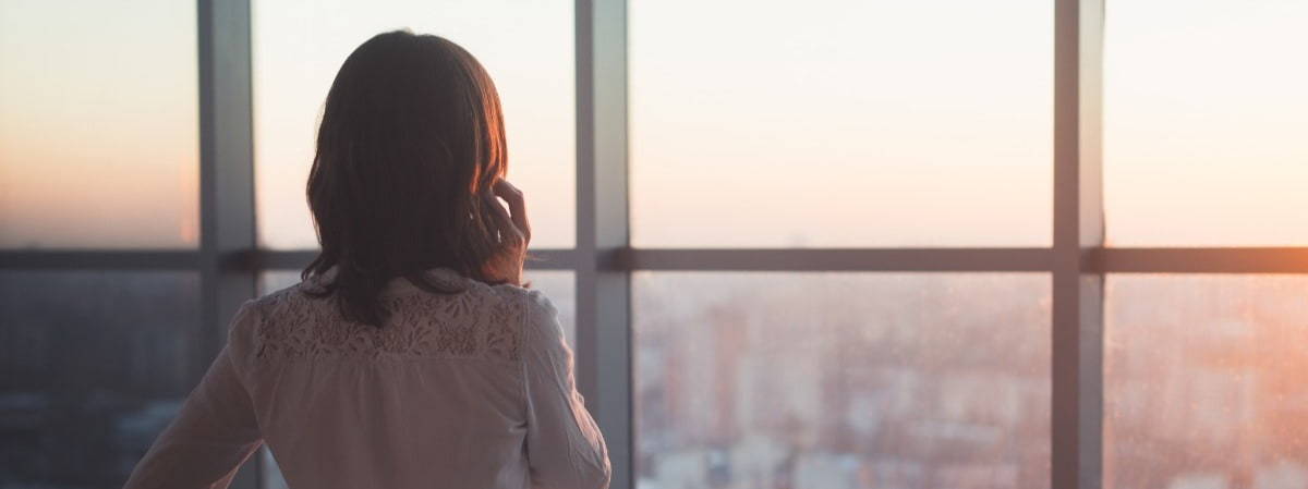 Working professional looking out office window while on the phone 