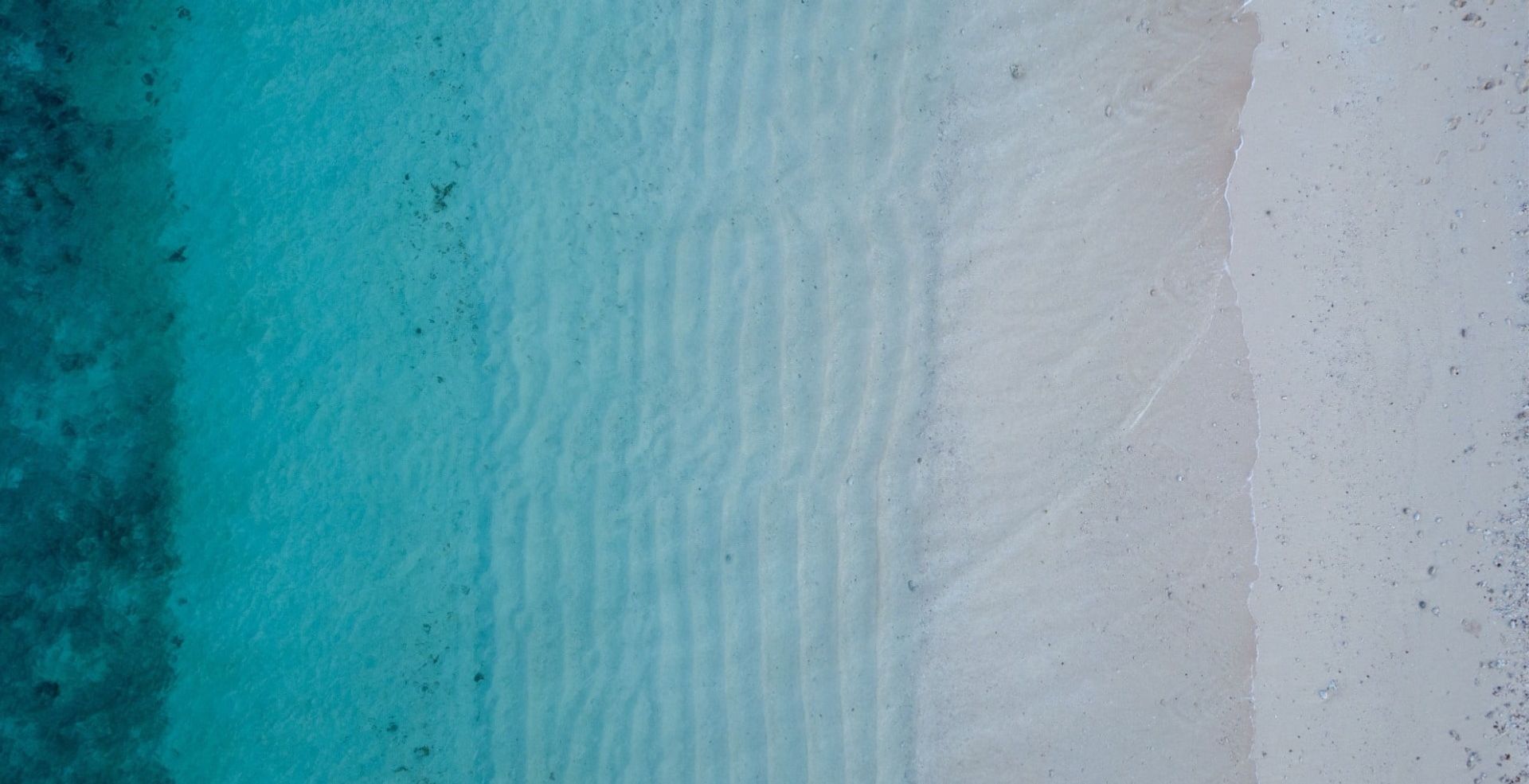 bird's eye view of gradient turquoise waves with beach