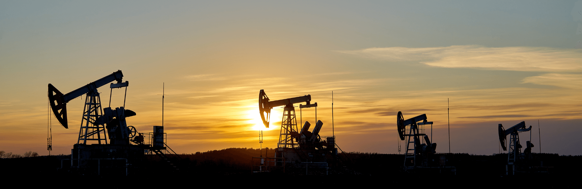 Oil field with four Derricks in sunset skyline