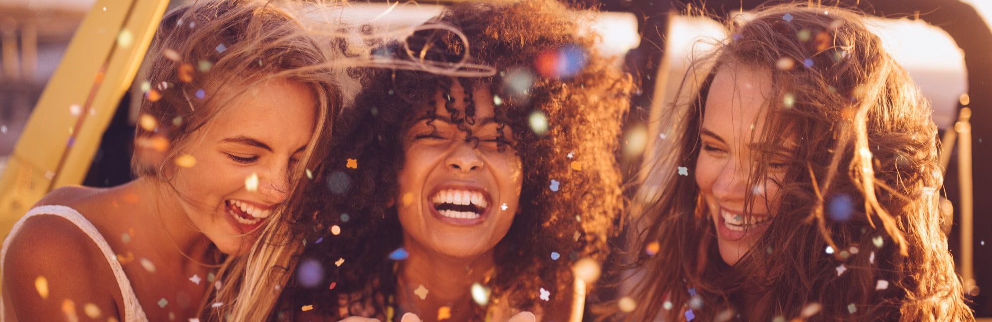 Blog Header Image - three people outdoors smiling with colourful glitter and confetti