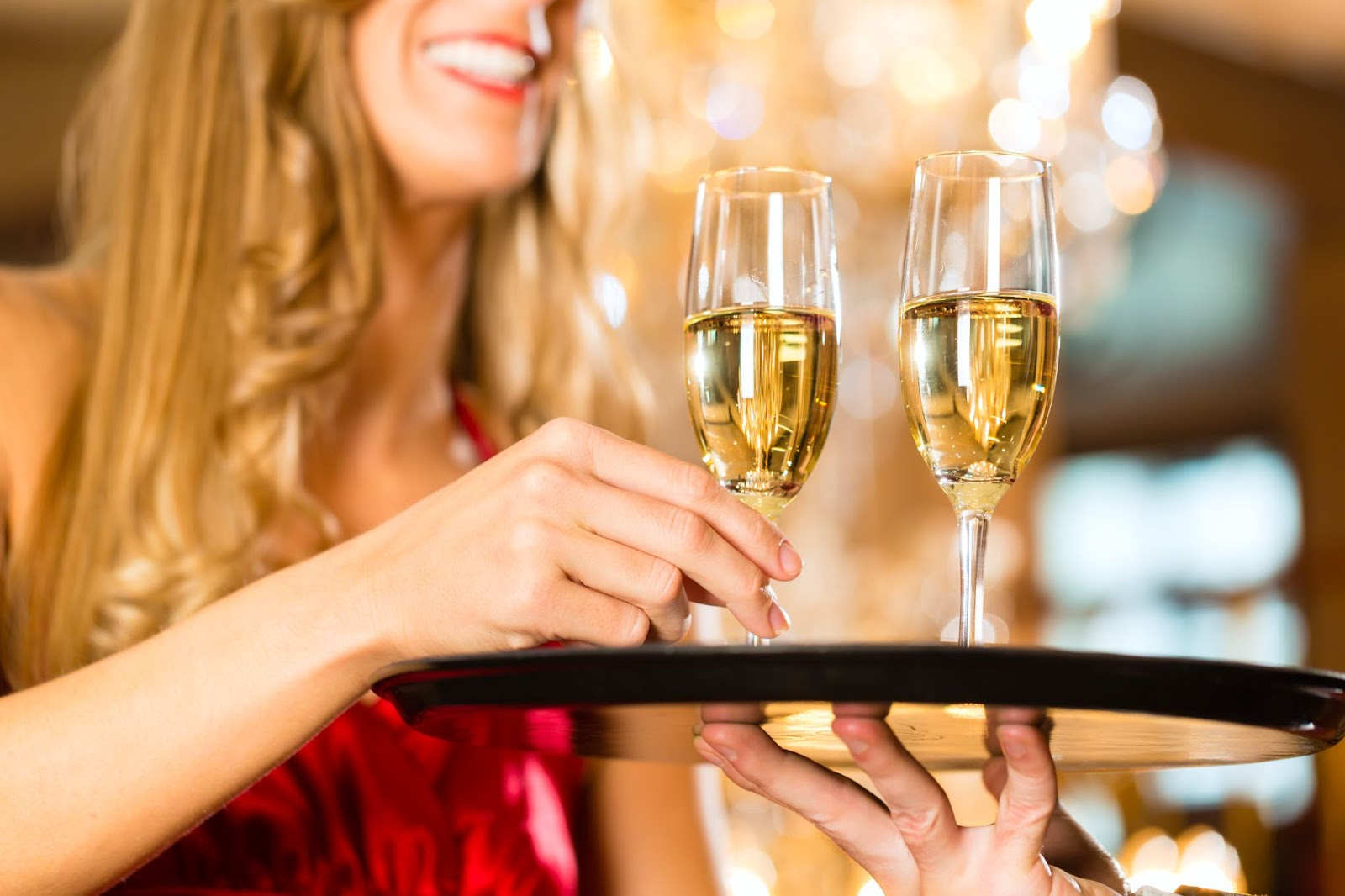Woman holding champagne glass on tray.
