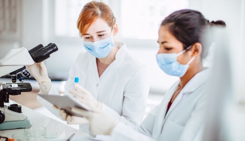 2 women in lab coats analysing data