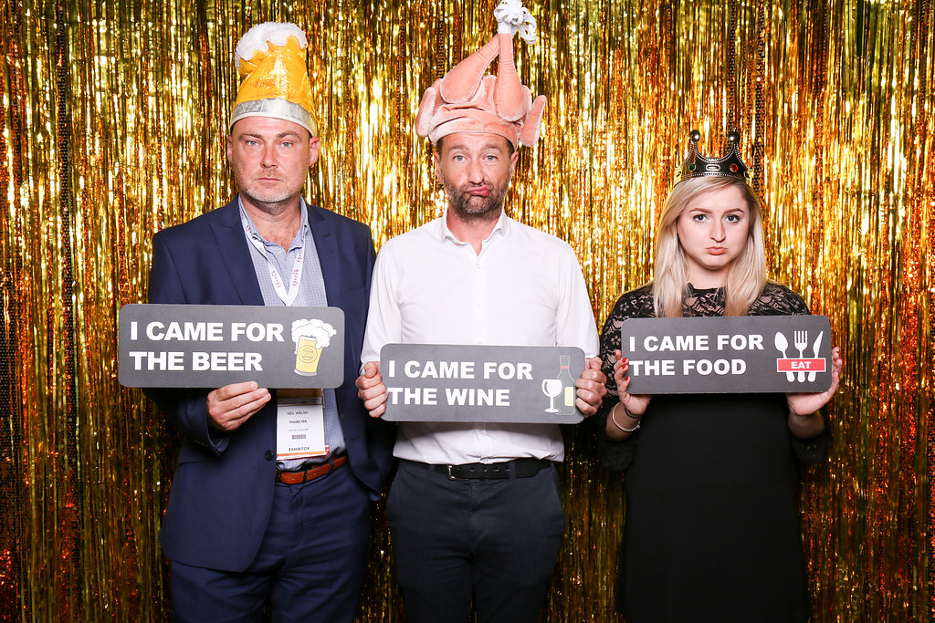 Photobooth photo with two men and a woman holding signs
