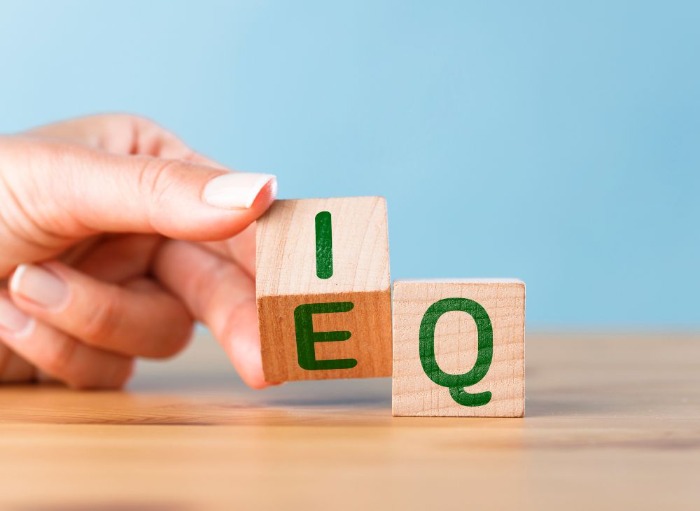 hand turning wooden lettered blocks E and Q that represent emotional intelligence