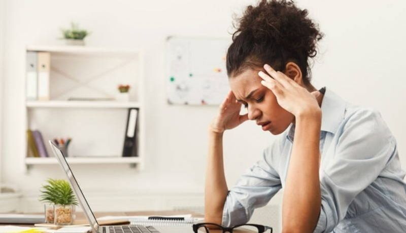 Stressed woman holder her head with her elbows resting on her desk 