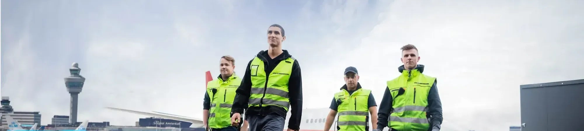 four working men on the platform on Schiphol with yellow jackets .