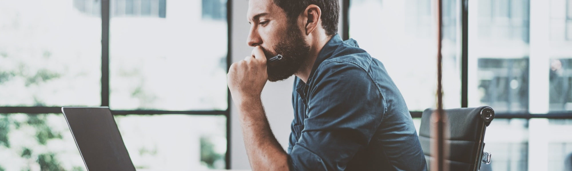 business man sitting on chair looking at laptop preparing for job interview