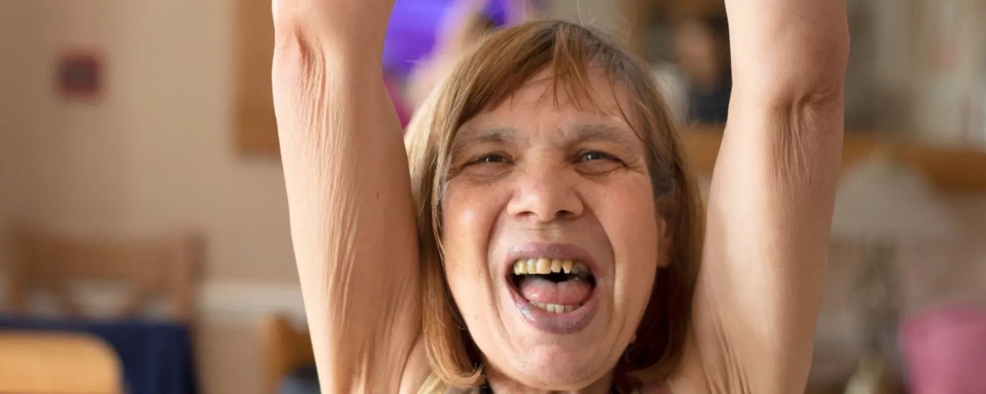 A woman with learning disability raises her arms to the air and cheers