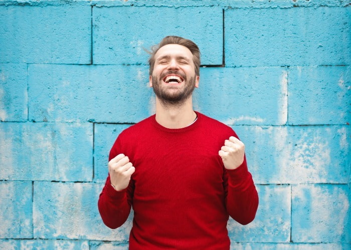 very pleased man leaning against blue wall
