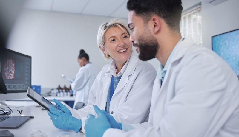 Professional man and woman in lab coats discussing data