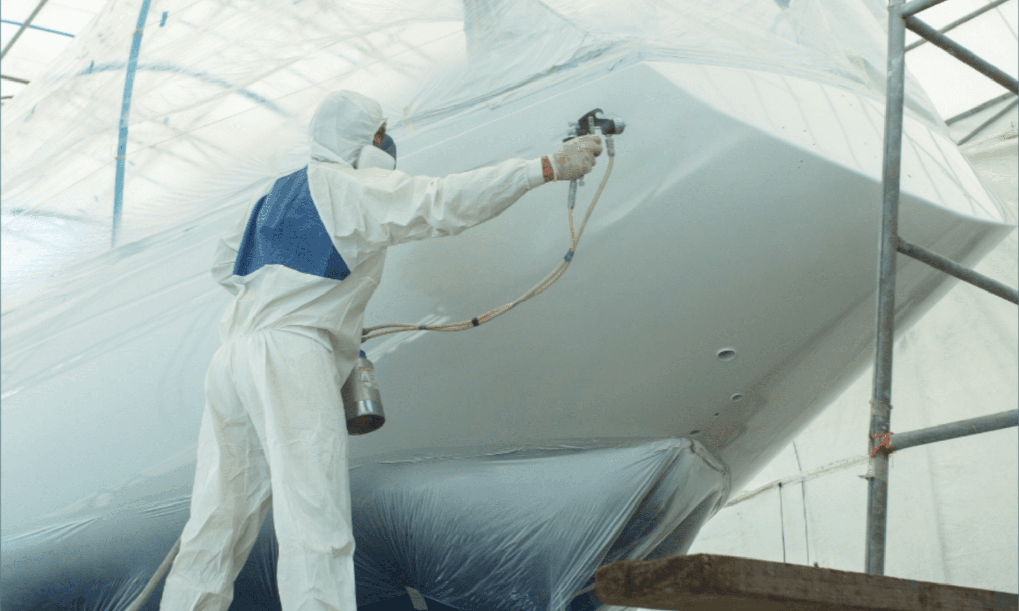 worker applying boat coating and finishing