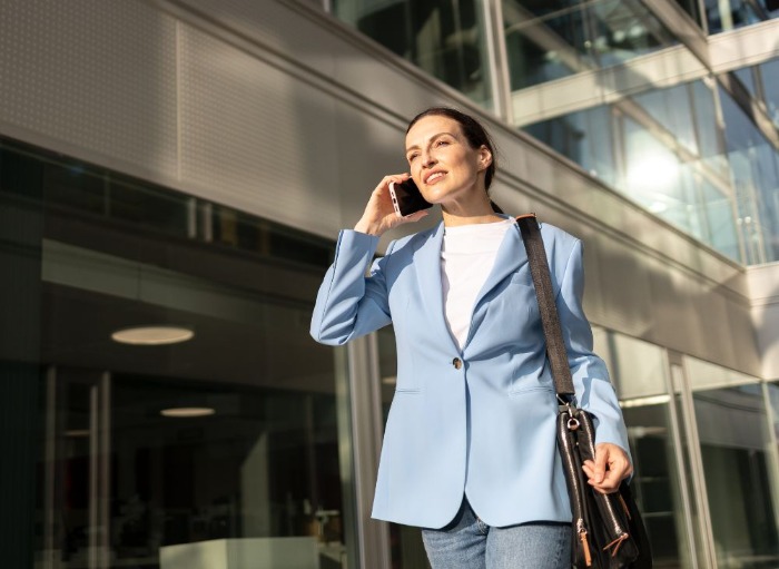 business woman in pale blue suit on mobile phone outside office