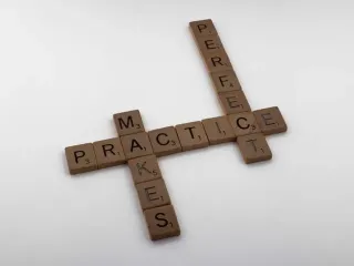 Scrabble letters arranged to spell "perfect practice" on a plain white background.