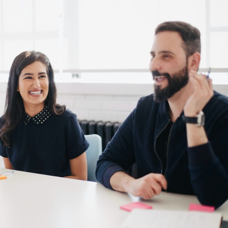 A smart female accountant sits next to a male finance co-worker in a meeting