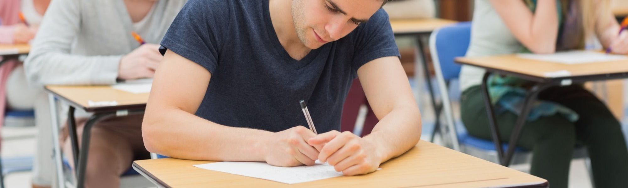 college student or graduate completing assessment paper as part of job application