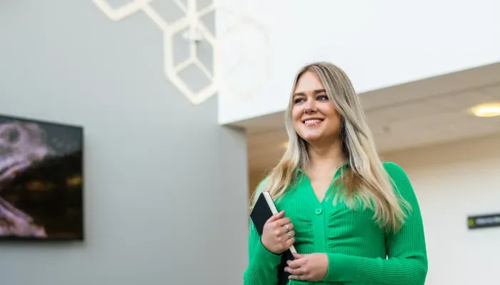 person smiling holding book under arm