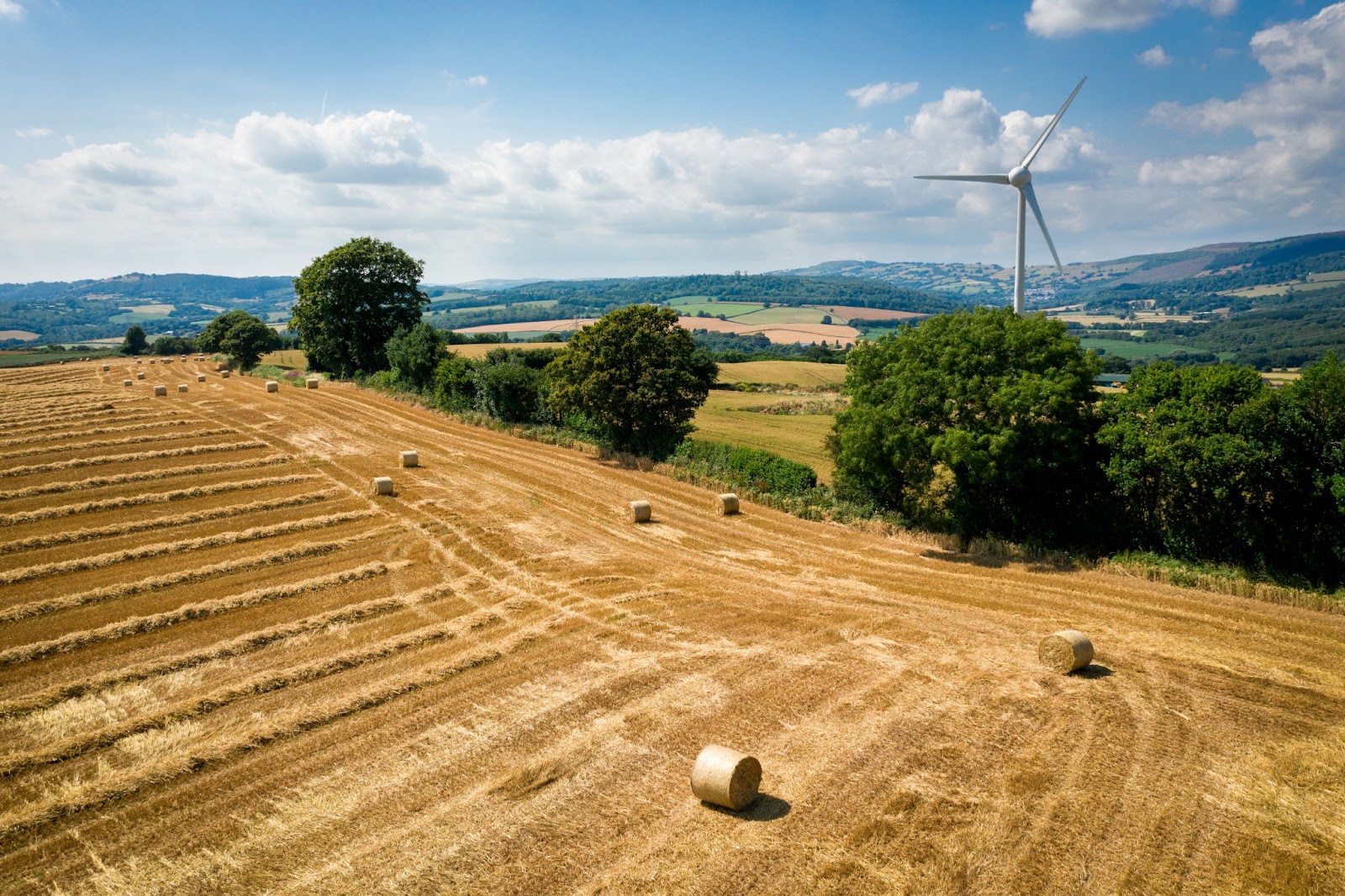 British countryside view showing farmers field, hay bales and a wind turbine on a sunny day