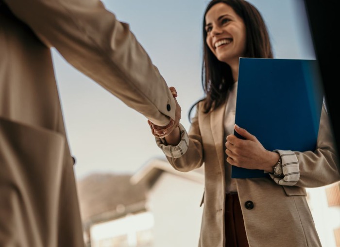 women in trenchcoats shaking hands