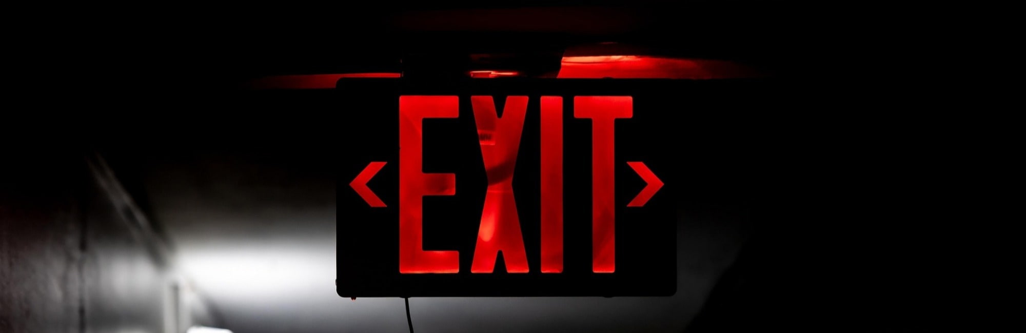 A bright red exit sign illuminated in a dark environment, indicating the way out.