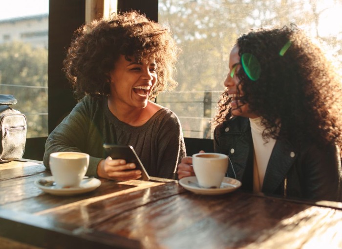 Two women meeting and laughing over coffee