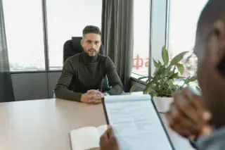 A man sitting at a desk with a clipboard, conducting an exit interview.