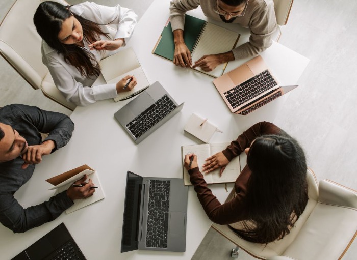 Group of workers meeting round a table with laptops