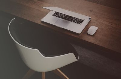 modern white chair in front of wood desk with laptop and mouse