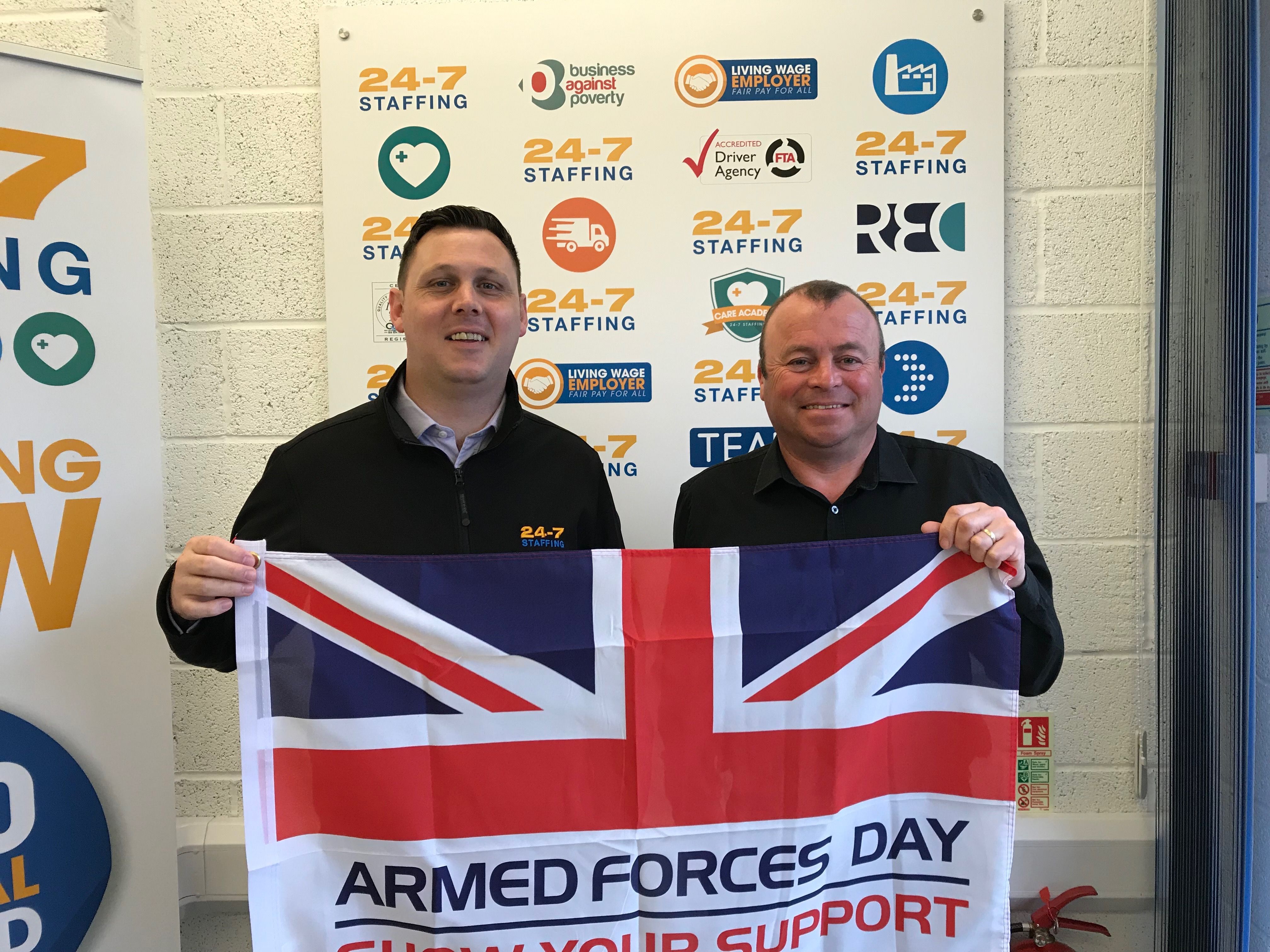 Image of two consultants holding Armed Forces Day flag 