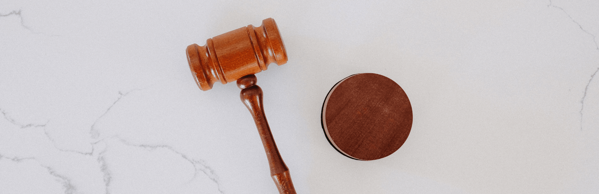 Wooden gavel alongside a disc on a white marble background, illustrating the theme of good judgment.