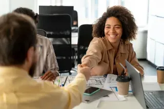 Two people engaged in a handshake at a meeting, representing a successful introduction and a positive connection.