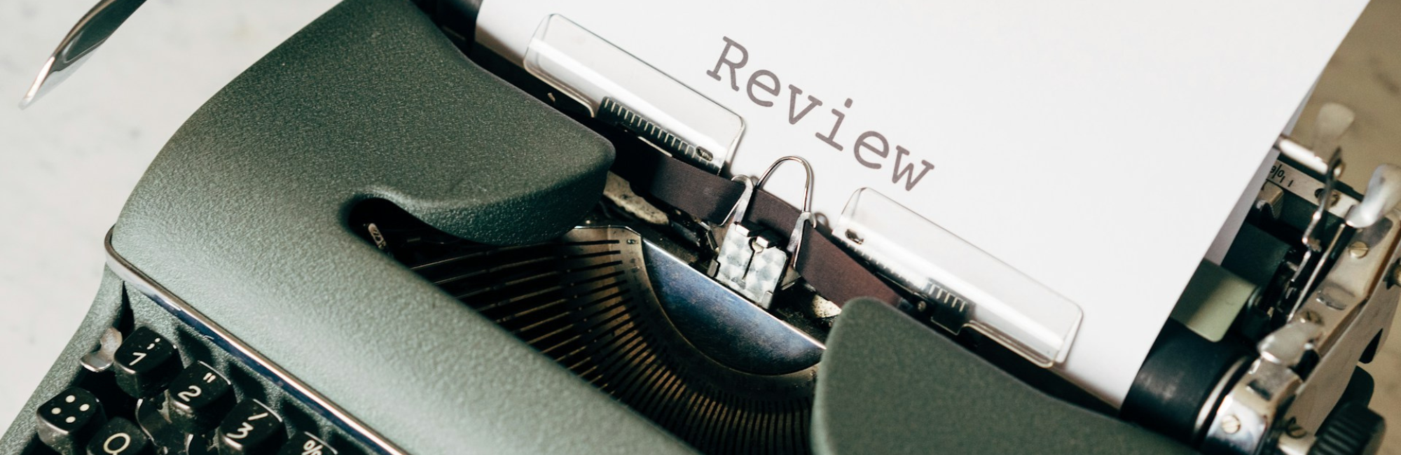 A typewriter displaying the word "review," representing the concept of work reviews and evaluations.